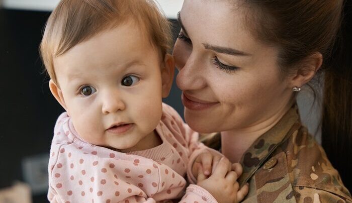 Young military woman holds a little girl in her arms, a mother in a camouflage uniform