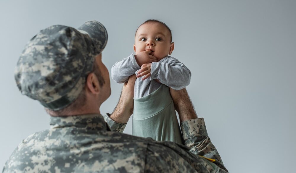 army soldier in military uniform and cap holding baby son in arms isolated on grey,stock image