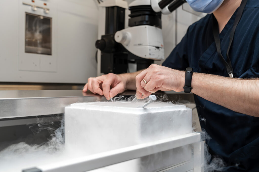 Embryologists working with a liquid nitrogen tank used to store frozen eggs.