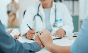 Doctor holding hands with a couple during a fertility consultation.